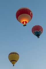 Three hot air balloons fly against the blue sky in Pamukkale, T&uuml;rkiye