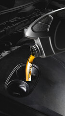Close up of golden motor oil pouring from plastic container into car engine opening. Concept of...