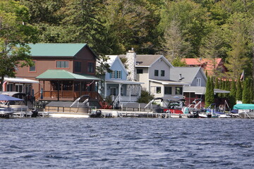 Obraz premium A row of closely packed houses sitting directly on a lake in the Adirondacks on a sunny day in late summer.