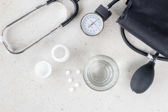 Blood pressure monitor, stethoscope, glass of water and white pills, healthcare and pharmacy concept showing treatment, prevention, medical examination and daily medication routine