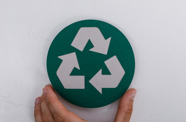 Close-up of a hand holding the recycling symbol, perfect for illustrating sustainability,...
