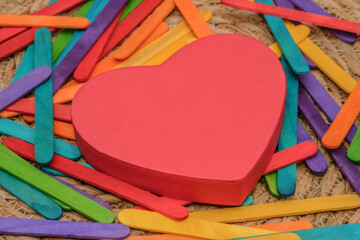 The heart-shaped box centered on a bed of scattered, colorful sticks. All resting on a woven straw...