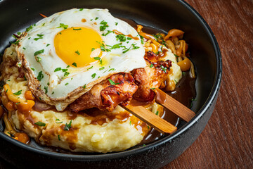 A plate features mashed potatoes, a fried egg, and tasty meat skewers with herbs