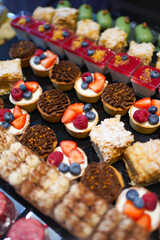 Various colorful desserts with berries, chocolate, and cream on display, a delicious sweet collection of pastries.