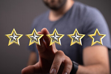 A hand touches four gold stars, representing a high rating or positive review. Concept of...