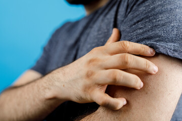 Close up shot of a man scratching his arm indicating skin irritation and itching. The image conveys discomfort, healthcare, and health concerns.