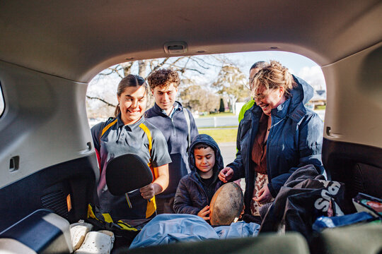 Mixed ethnicity family unpacking car boot