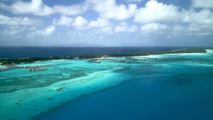 Luxury resort photos of Bora Bora tropical paradise islands
with palm trees, thatched bungalows. Aerial 
perspective photography, coral reef, azure ocean, 
sky with clouds on horizon. French Polynesia