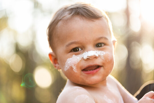 Smiling happy portrait of young Aboriginal toddler boy in ochre paint outdoors 