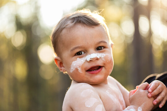 Smiling happy portrait of young Aboriginal toddler boy in ochre paint outdoors 
