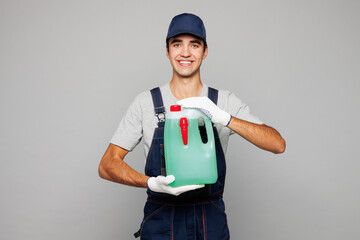 Young smiling car mechanic man wear overall hat uniform workwear clothes work in garage holding in...