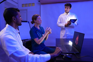 group of two male and one female doctors of various nationalities sat in a meeting, debated, and the male doctor presented his work in a conference room and studied research data on treating patients 