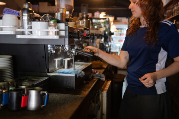 young barista in a cafe behind the coffee machine