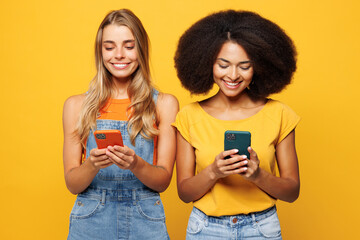 Two young friends buddies women wearing denim casual clothes together hold in hand use mobile cell...