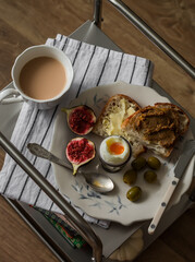 Delicious breakfast - boiled egg, toasts with liver paste and butter, olives on a metal table