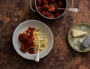 Beef meatballs in tomato sauce and spaghetti pasta - a delicious lunch on a wooden table top view