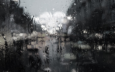 Raindrops on the glass create a dreamy bokeh effect with colorful car lights and reflections, capturing the beauty and melancholy of a rainy evening in the city.