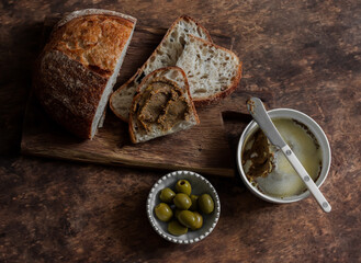 Delicious breakfast, snack, appetizer, tapas - tartine bread, liver paste, olives on a wooden table