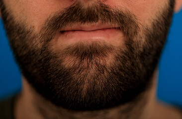 Obraz premium A close-up shot featuring a man's beard, lips and facial hair detail, showcasing the texture and style. Focus on the groomed appearance and masc