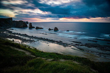 Dramatic coastline at dusk with stunning rock formations and moody skies, offering a sense of...