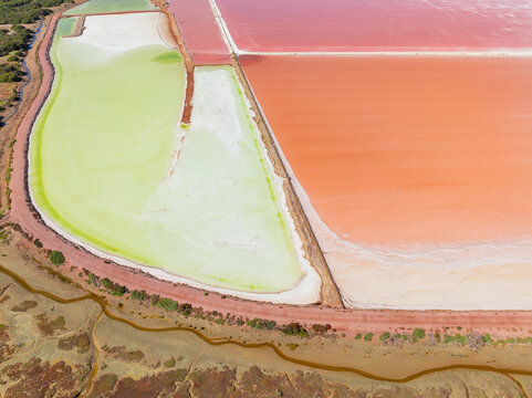 Aerial view of colourful salt evaporation ponds and levee banks at a coastal salt farm