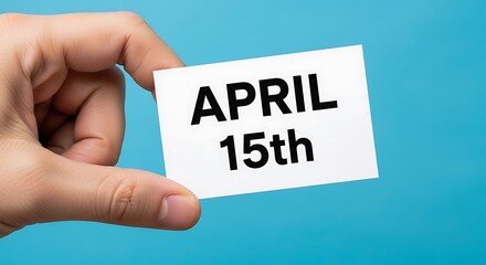 Hand holding a card with the date april 15th written on it against blue background