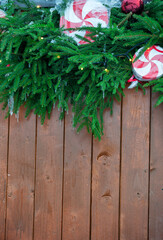Festive pine garland decorates rustic wooden background with red ornaments