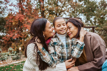 Fototapeta premium Mother, grandmother and granddaugter standing in autumn garden.