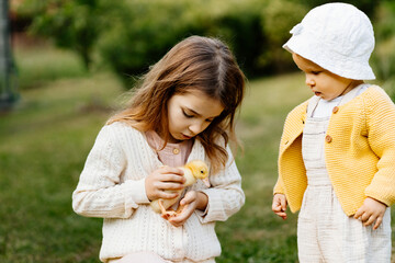 Older sister showing little ducklings to toddler girl.