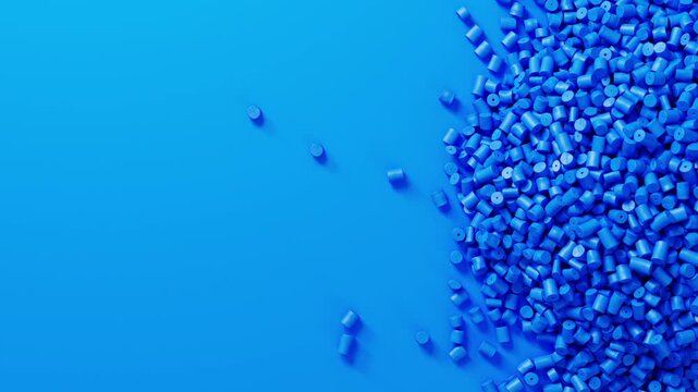 Closeup top view on blue plastic polypropylene granules heap rotating on blue backdrop, masterbatch polymer grain pile. HDPE or PVC resin pellets.