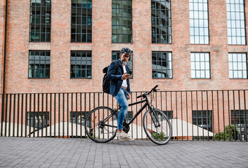 Fototapeta premium City commuter riding bike from work, reading text message on phone.