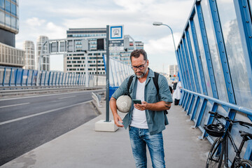 Mature man walking home from work, texting on smartphone.
