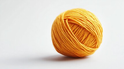 Yellow yarn ball on white background for craft projects, displayed on a studio background