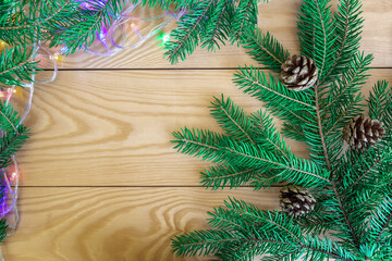 Christmas tree branches with golden balls and cones decorate a wooden background