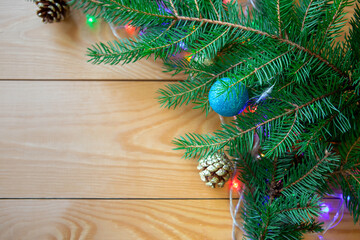 Green spruce branches with golden balls, cones decorate the wooden background