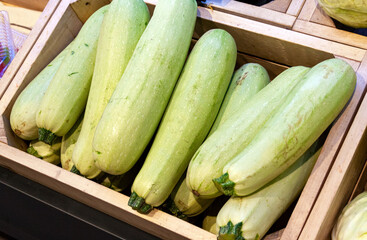 The zucchini is light green in color neatly stacked in a wooden box