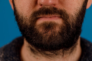 Obraz premium Detailed close-up of a man's beard, showcasing the texture and color. The image focuses on the facial hair, emphasizing its fullness and dark to