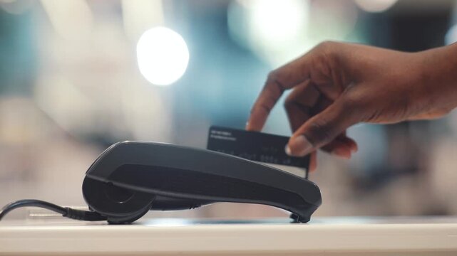 Customer Hand Making Contactless Payment with Credit Card on POS Terminal