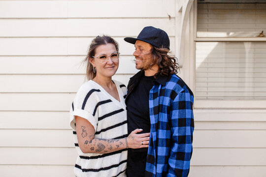 Happy couple standing outside white weatherboard home