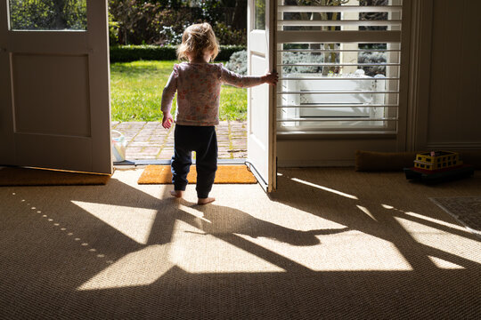 Toddler girl opening the door to the garden
