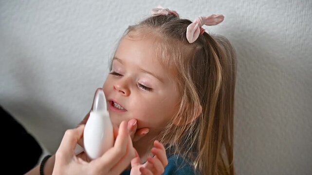 Mother using nasal aspirator also known as snot sucker for her cute toddler girl at home. Full HD slow motion video footage