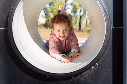 Little child crawling through the tunnel in the playground