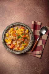 Hot chicken stew or soup with tender chicken pieces, chunky potatoes, and vibrant carrots garnished with fresh parsley in rustic bowl, comfort food for autumn and winter