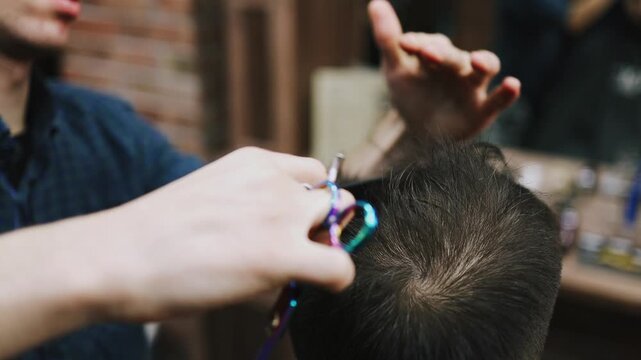 Hairdresser cutting a male client's dark hair with scissors and comb in a modern barbershop, close-up on hands and head highlighting precision, style and professional grooming