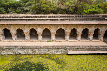 Fototapeta premium This landscape photo was taken in Asia, India, Delhi, Delhi, in summer. It shows the Rajon Ki Baoli stepwell of the Mehrauli archaeological complex in Delhi, under the Sun.