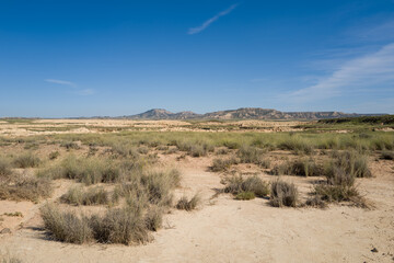 This landscape photo was taken in Europe, Spain, Navarre, in summer. It shows the arid field in the Bardenas Reales, under the Sun.