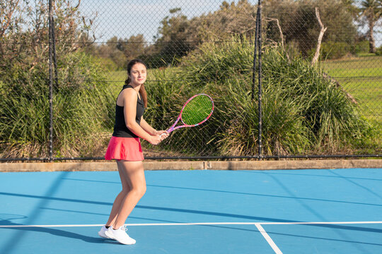 young woman playing tennis outdoors on a blue court