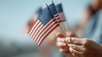 Hands waving small american flags on sticks celebrate a patriotic event, with a blurred crowd in the background embodying unity and national pride amid the festivities
