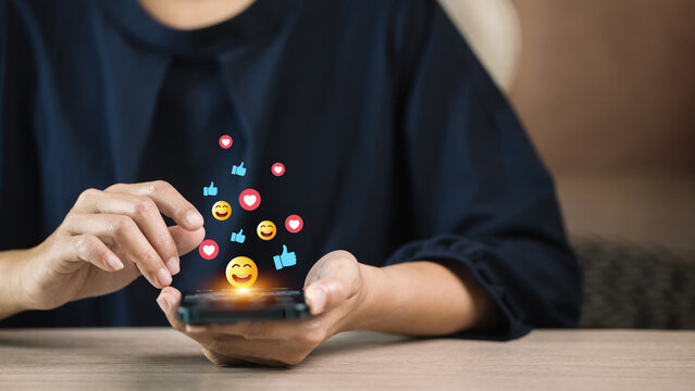Woman using smartphone with social media emojis floating concept of online communication and digital marketing