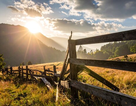 Rustic wooden fence at sunset with golden rays over rolling hills